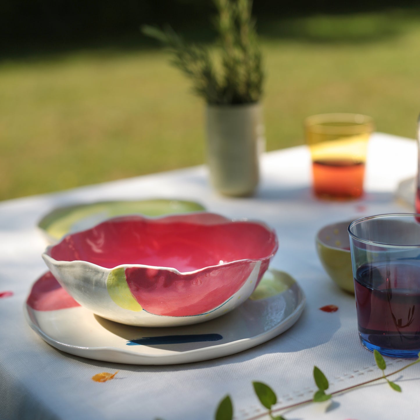 A colorful porcelain bowl with a floral design, predominantly red, displayed on a table with other dinnerware in the background.