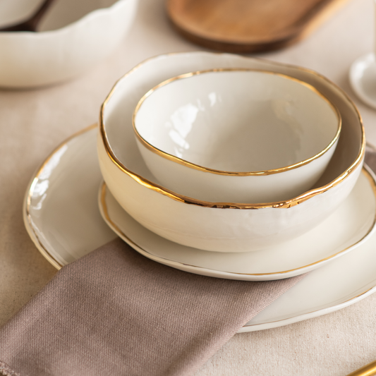 Set of white ceramic bowls with gold rims ready for lunch